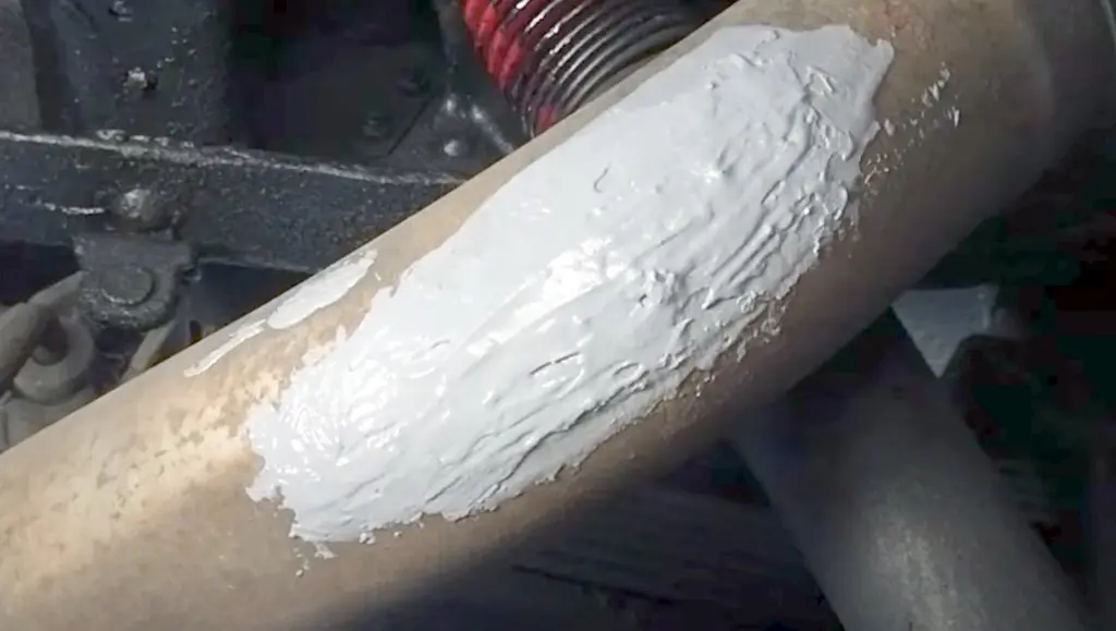 applying muffler cement to the exhaust leak
